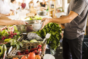 seller-hand-holding-stainless-steel-container-while-customer-buying-vegetable-market